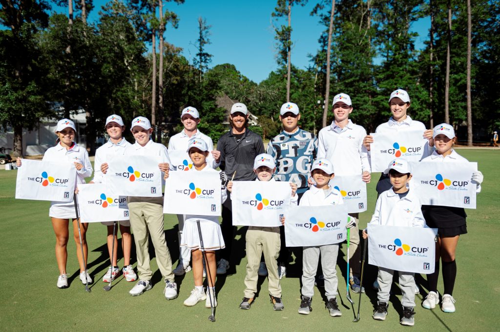 Kim Si-woo among with young golfers who are holding a flag showing THE CJ CUP logo