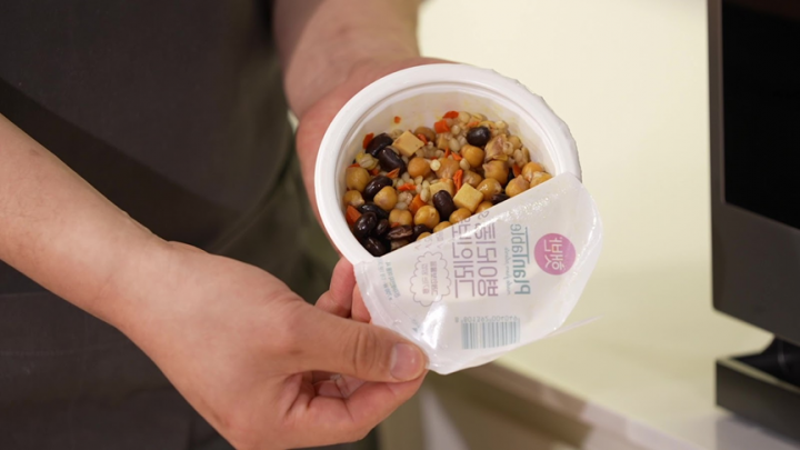 A person holding a plastic container of food
