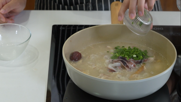 adding scallions onto the Samgyetang 