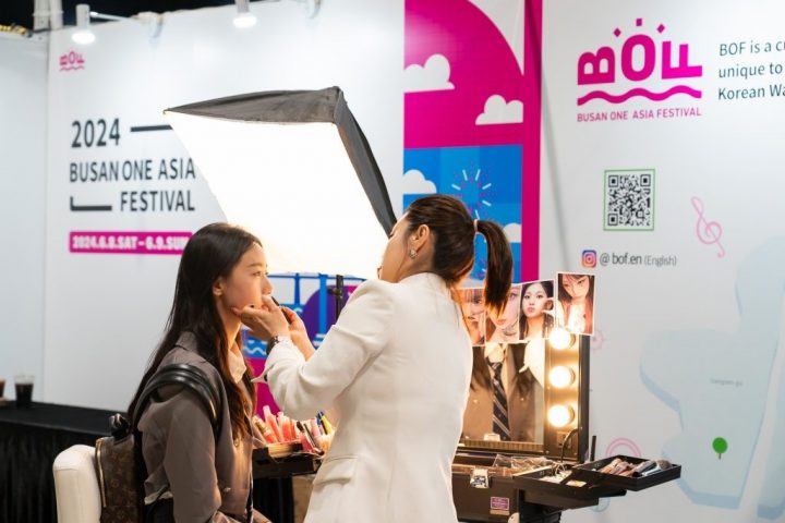 A photo of participants learning about Korean makeup, fan on the left, artist on the right. 