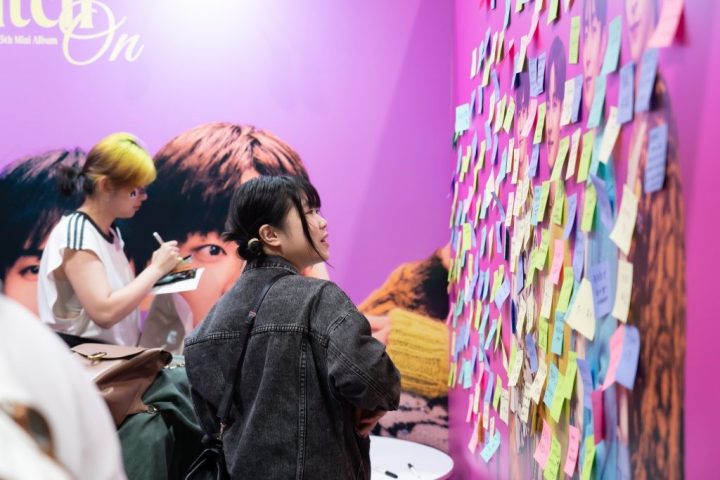 Attendees writing messages on a sticky note for their favorite idols