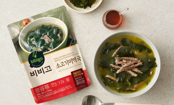 Image of bibigo 500 gram bag of seaweed soup with a bowl of cooked seaweed soup nearby.