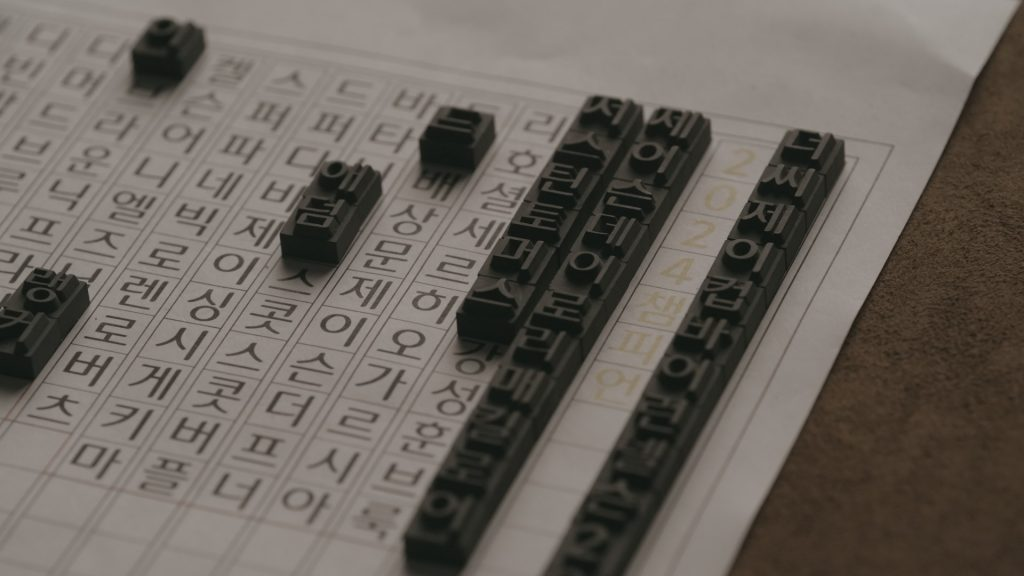 Metal type is shown on a page with hangeul writing, on a table. 