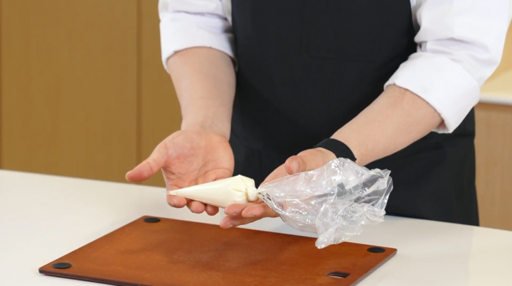 Cilantro cream cheese mixture added to a plastic bag prepared to be piped. 
