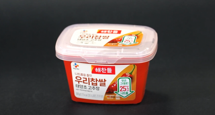 Container of gochujang paste with a black background.
