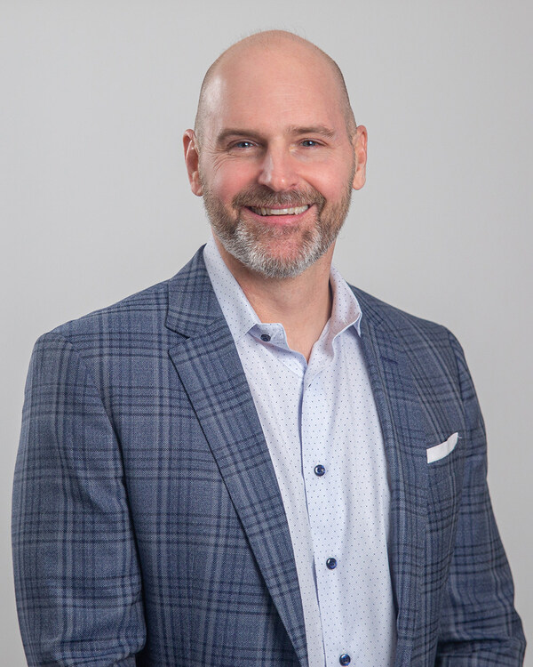 Image of bald man with beard in dark blue checkered over coat smiling