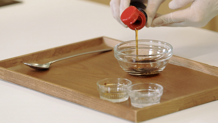 A chef mixes sugar, soy sauce and sesame oil in a bowl. 