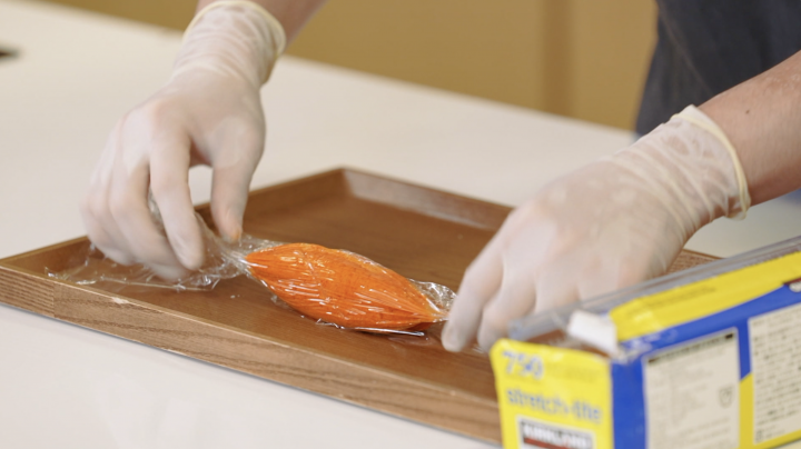 A chef shapes gochujang butter into a cylinder. 