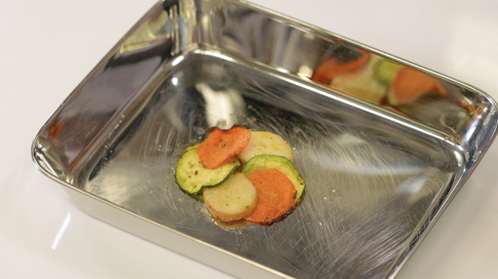 A cheesy vegetable gratin is layered in a baking tray