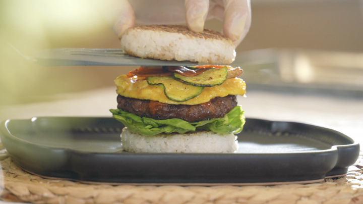 A tteokgalbi rice burger is assembled on a plate. 
