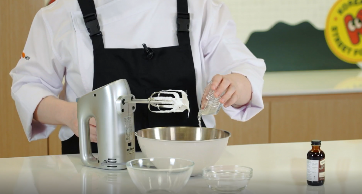 Pastry chef adding lemon juice to the meringue mixture.