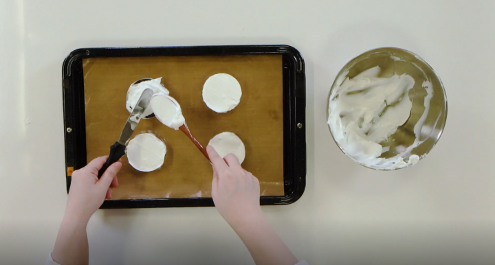 Meringue being shaped on a baking sheet.
