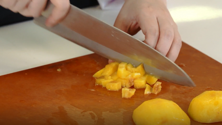 Peaches are cut into cubes with a knife
