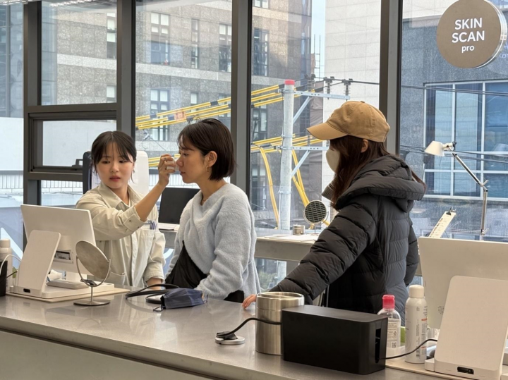 A beauty consultant at Olive Young N Seongsu conducts a personalized skin analysis for a customer.