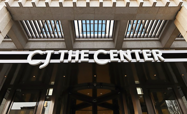 Outside a CJ building with the sign, “CJ THE CENTER” in white above the doors.