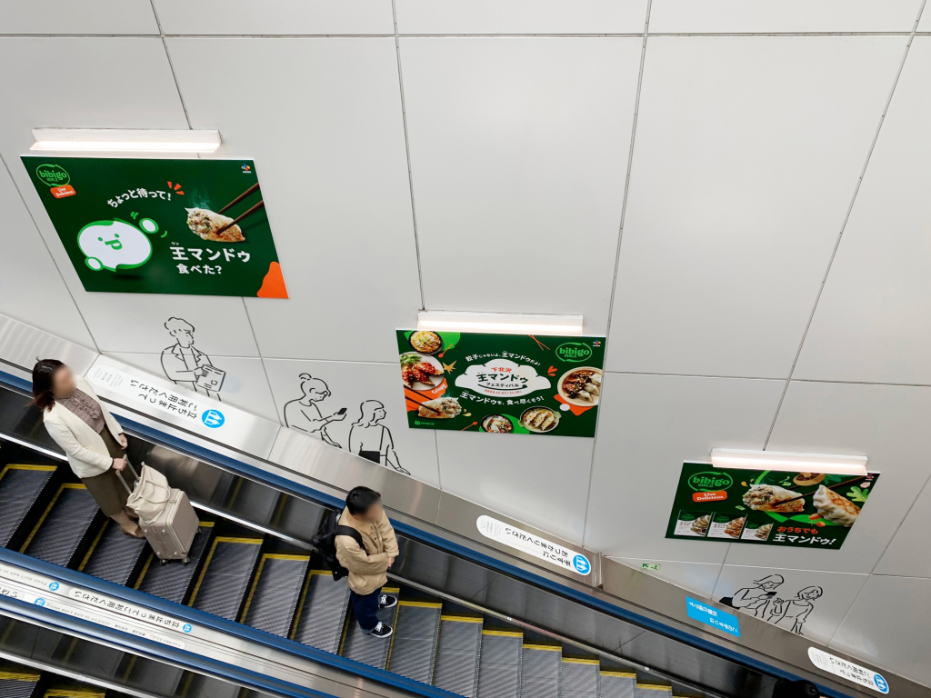 bibigo ads along an escalator in a Japanese metro station
