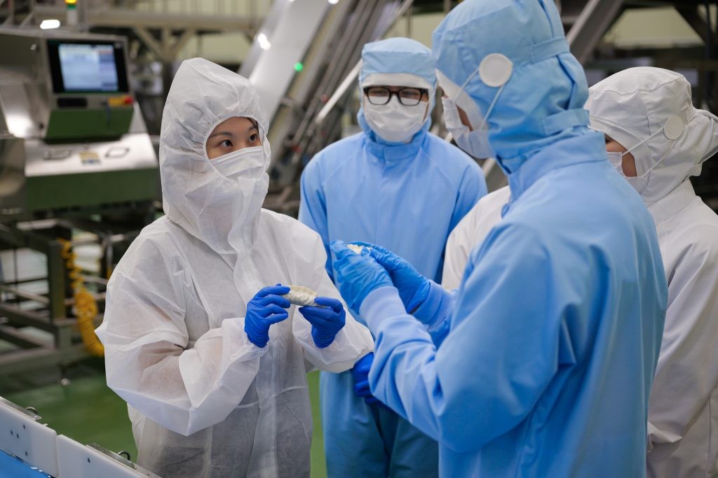 Several facility workers talk to each other while holding bibigo Mandu.