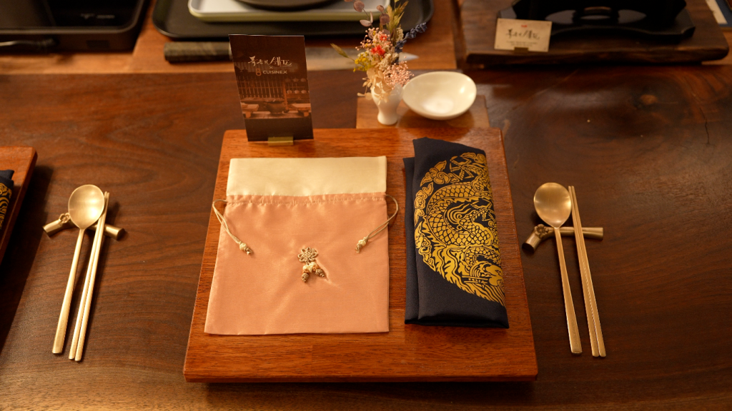Gold utensils and elaborate napkins for each diner, set on the dining table.