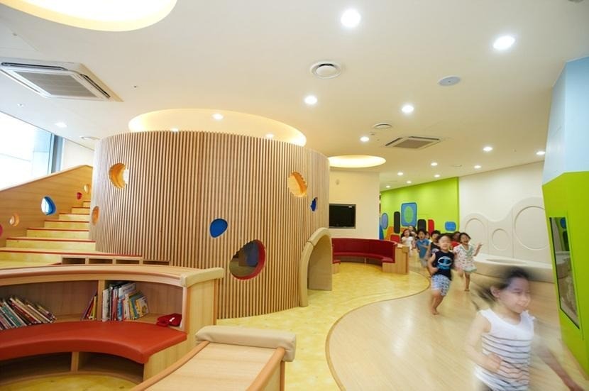 A children’s daycare with a modern interior design and several children running across the room.