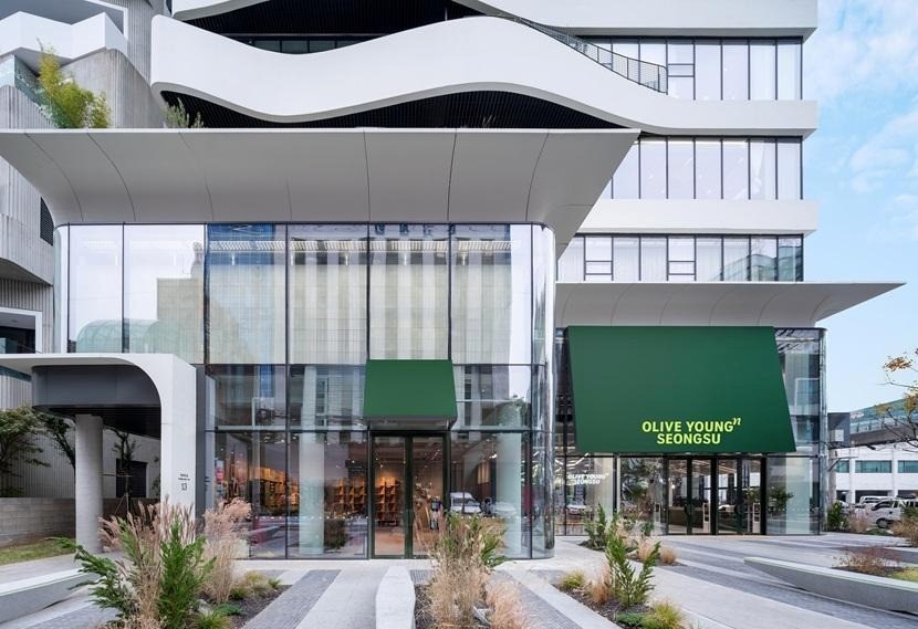 An external shot of Olive Young Seongsu, showing a multi-story building with floor-to-ceiling windows and modern architecture.