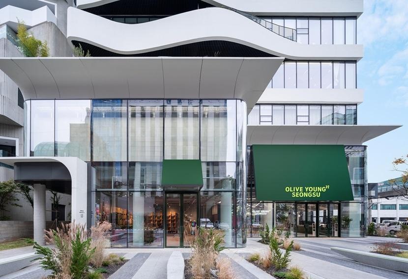 An external shot of Olive Young Seongsu, showing a multi-story building with floor-to-ceiling windows and modern architecture.