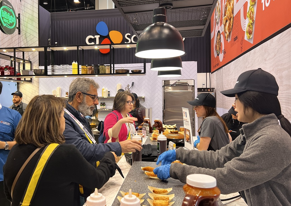 Customers talk to bibigo employees as they pick up mandu samples at the National Restaurant Association show