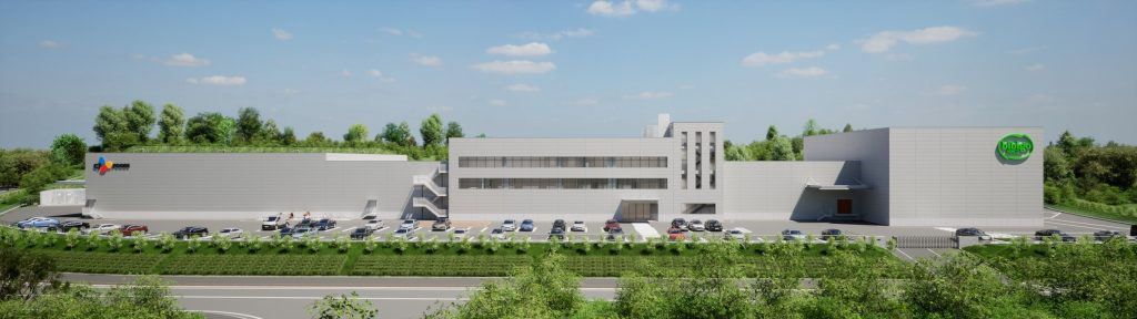 An external view of CJ Foods’ new plant in Chiba, Japan: a grey complex behind a parking lot, surrounded by trees
