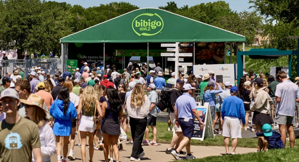 A crowd walks around a bibigo concession stand tend
