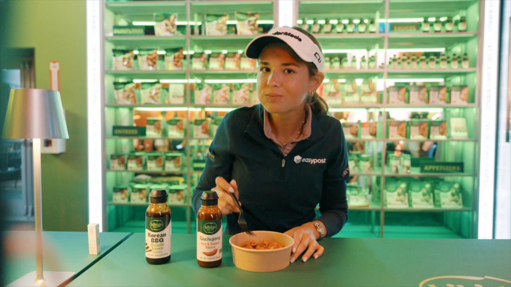 Kai Trump eats bibigo food and looks to the camera
