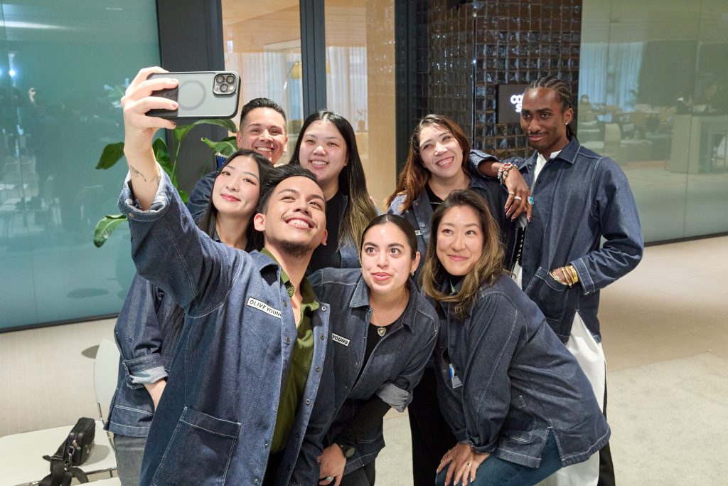 Eight U.S. store managers and assistant store managers pose for a group selfie during OLIVE YOUNG’s HQ training program in Seoul.
