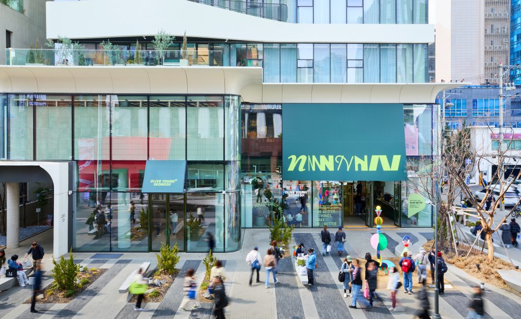 Exterior view of OLIVE YOUNG N Seongsu in Seoul, showing the glass-fronted store and people outside.