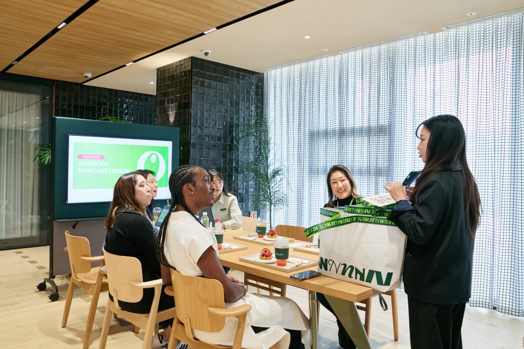 Future U.S. store managers and assistant store managers receive welcome gift bags from a training lead at OLIVE YOUNG N Seongsu in Seoul.