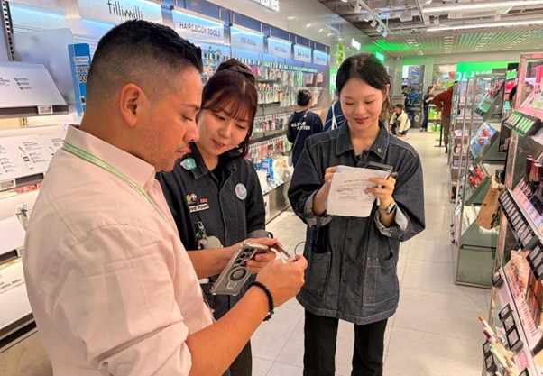 A U.S. store manager looks through K-beauty products with a buddy staff member during job shadowing.