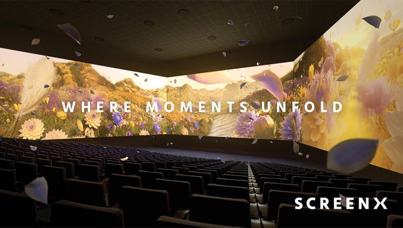 An empty SCREENX theater depicting drifting yellow and lavender flowers on-screen with the words “WHERE MOMENTS UNFOLD” written on top.