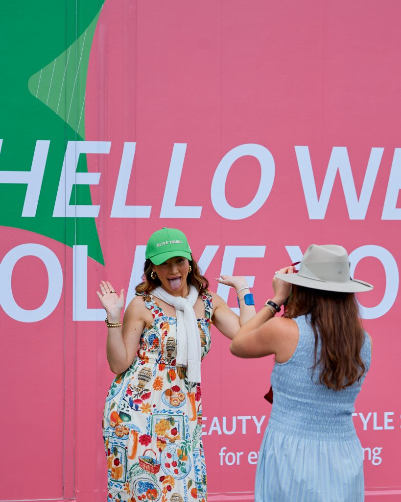 A visitor poses in front of the OLIVE YOUNG booth at THE CJ CUP.