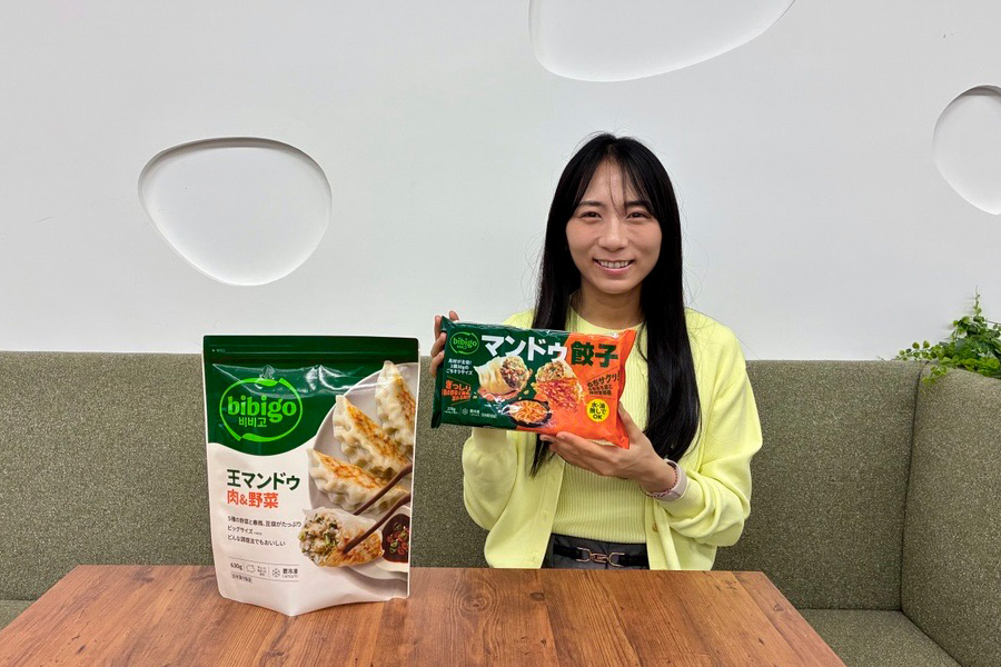 Ichikawa Sayo of CJ FOODS JAPAN holds bibigo Mandu Gyoza alongside a bibigo Korean-style mandu product during an interview.