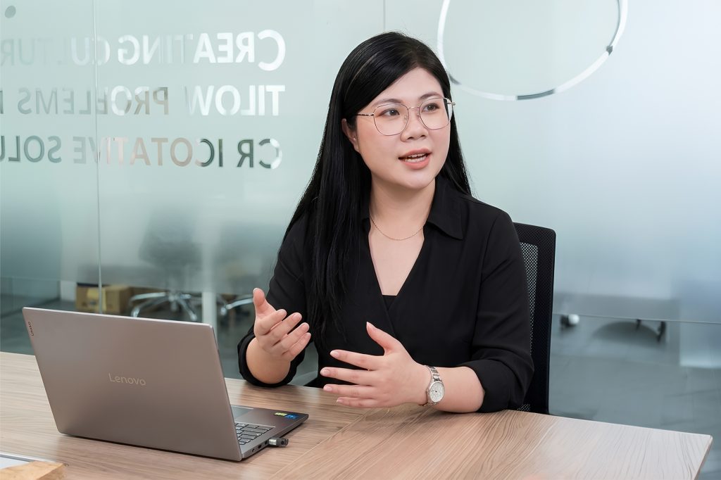 A CJ Foods Vietnam kimchi brand manager speaks during an interview at a conference table with a laptop nearby.