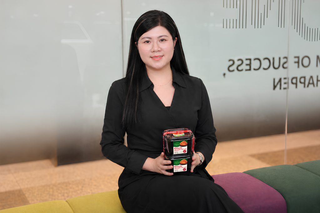A CJ Foods Vietnam kimchi brand manager holds packages of bibigo Kimchi during a newsroom interview.