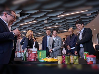 Chairman Lee Jay-hyun and other CJ and Schwan’s executives look at a spread of food on a table.