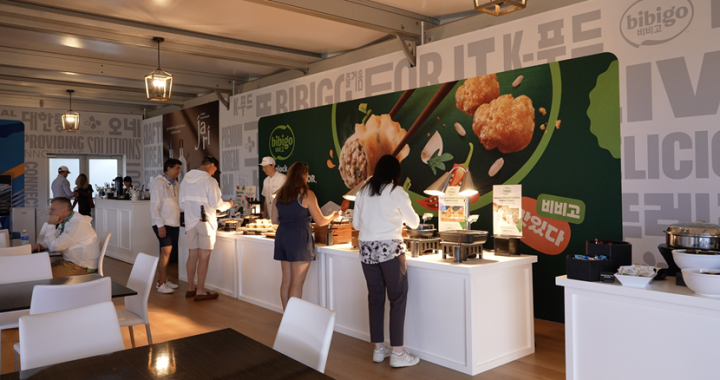 Visitors at CJ’s Hospitality Suite fill plates at a buffet set up by bibigo.