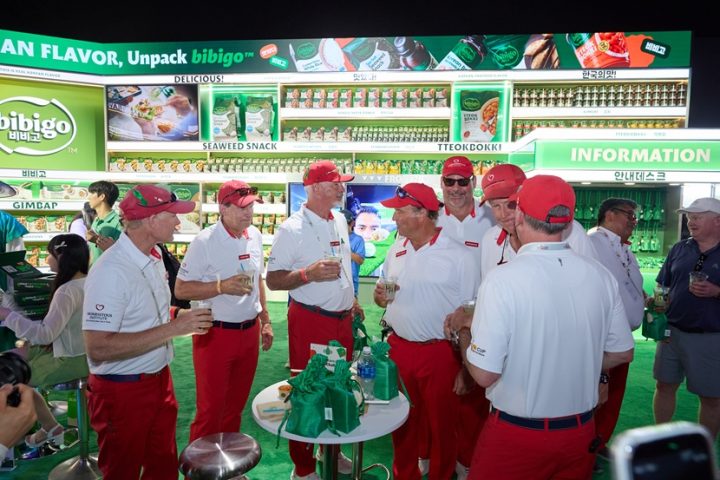 A group of men in matching uniforms enjoy drinks at a large bibigo booth.