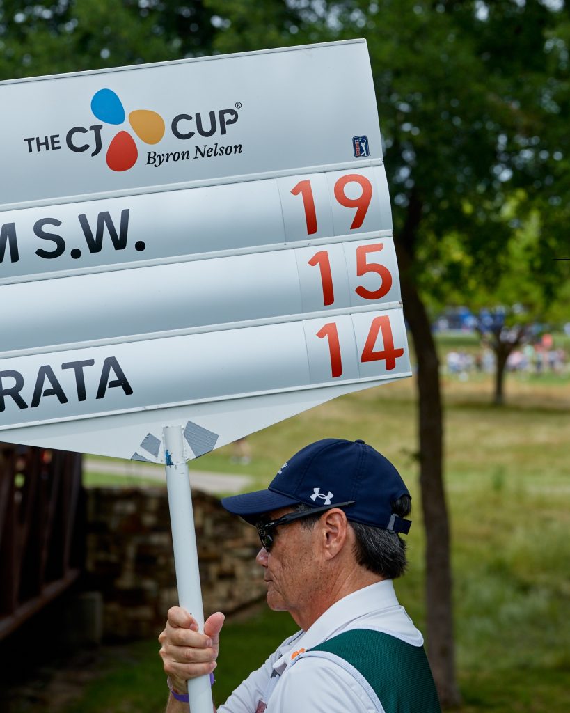 Volunteer carrying a leaderboard during THE CJ CUP Byron Nelson golf tournament.