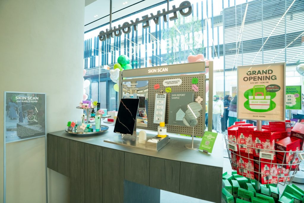 SKIN SCAN service area inside OLIVE YOUNG Century City, featuring product displays, skin analysis signage and grand opening promotions.