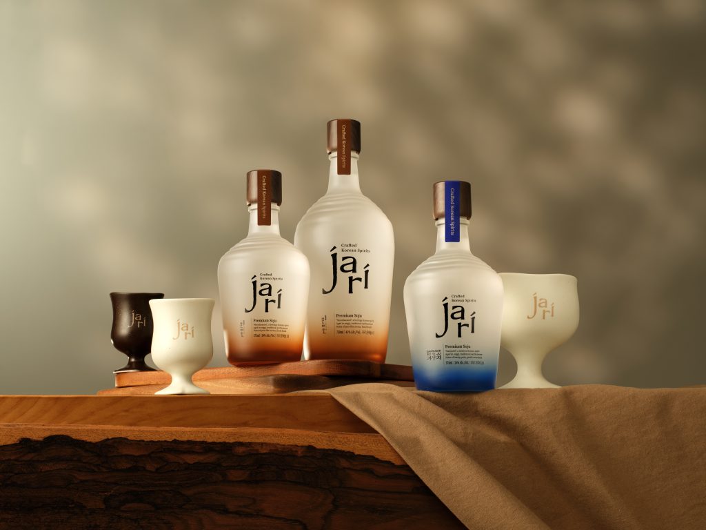 Two jari Premium Soju bottles with blue and amber accents displayed among dark ceramic spirit bottles