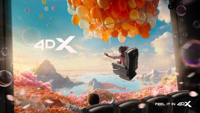 A 4DX screen showing a girl flying in a movie-theater seat through a fantastical land, held by a large grouping of balloons.