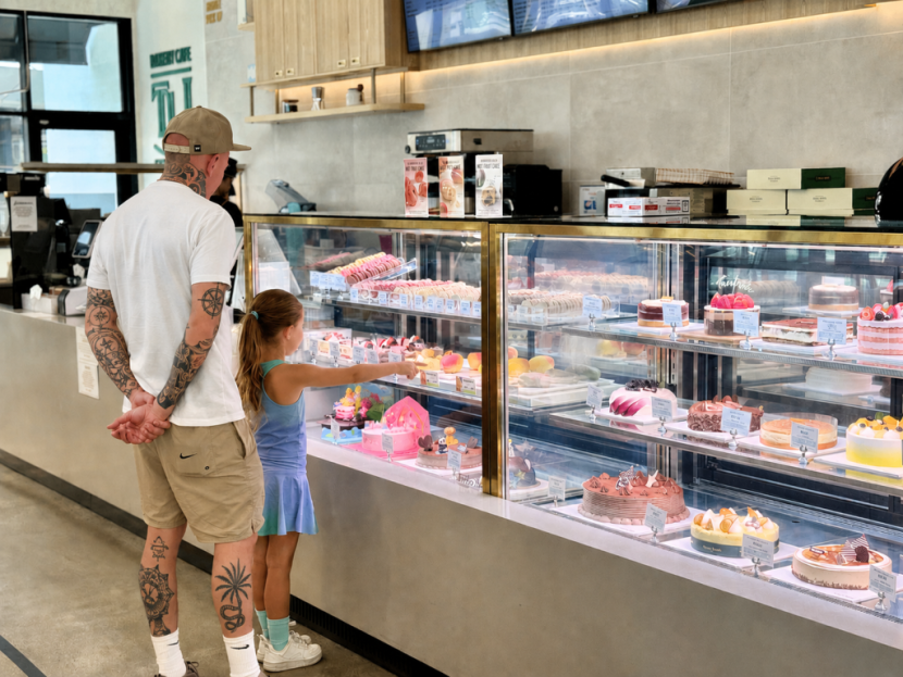 A man and girl look at the cakes on display at TOUS les JOURS.