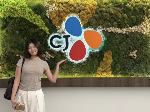 Baik Ju-eun poses for a photo in front of a CJ logo.