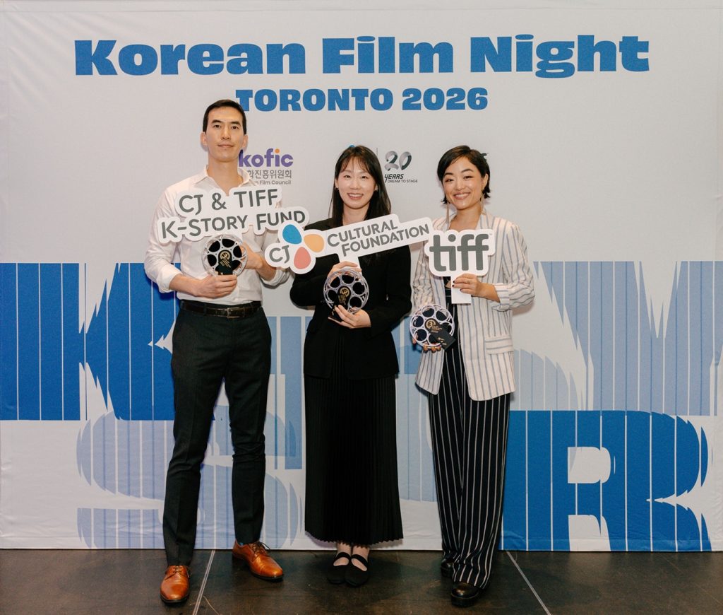 Josh Kim, Ji-yun June Lee and Andrea Bang pose for a commemorative photo at TIFF in front of a banner for Korean Film Night. Image (Photo courtesy of KOFIC)