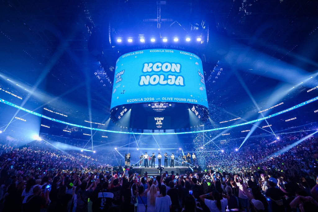 A concert venue at KCON LA 2026 packed with a large crowd, with a jumbotron displaying the tag “KCON NOLJA.” 